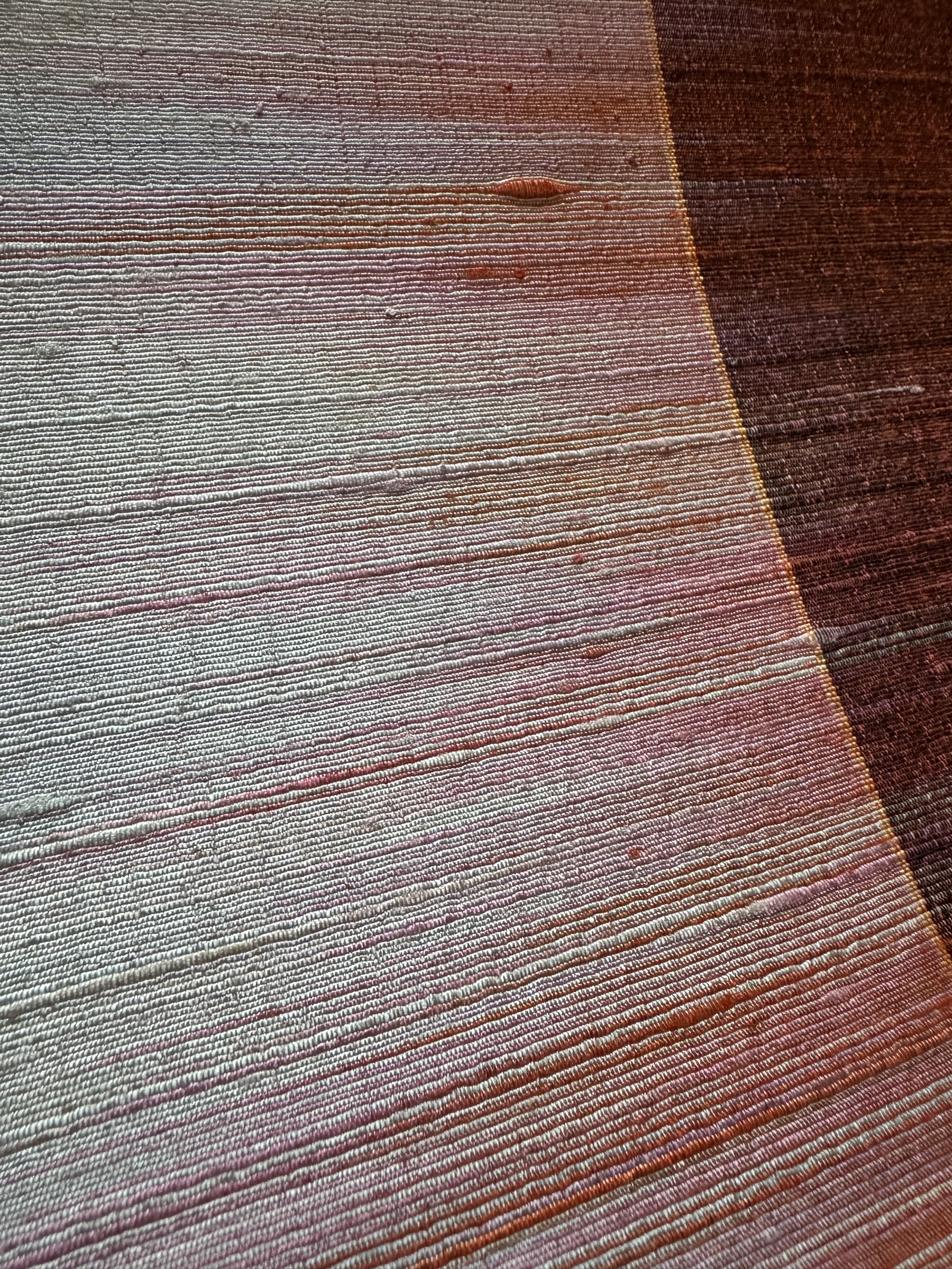 Close-up of a finely woven natural surface with soft mineral and rust-toned color movement